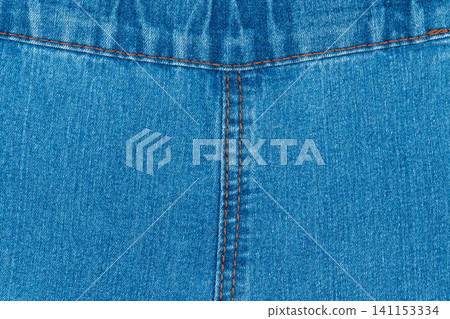 Blue denim fabric texture with symmetrical orange stitching and seam Blue denim fabric texture with symmetrical orange stitching and seam 141153334
