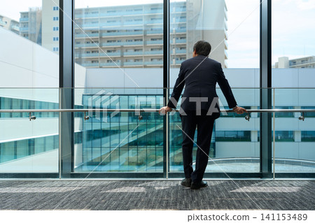 一位企業主正望著辦公室窗外。 141153489