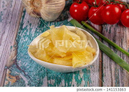Pickled ginger in white bowl with fresh garlic, tomatoes, and scallions on rustic wood table Pickled ginger in white bowl with fresh garlic, tomatoes, and scallions on rustic wood table 141153863