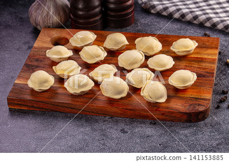 Raw dumplings arranged on wooden board with garlic and spices Raw dumplings arranged on wooden board with garlic and spices 141153885