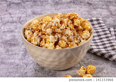 Caramel popcorn in ceramic bowl on stone table Caramel popcorn in ceramic bowl on stone table 141153908