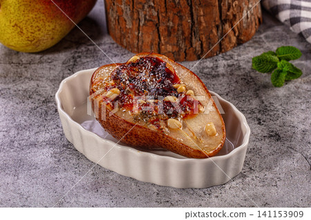Baked pear half with honey glaze and pine nuts in ceramic dish Baked pear half with honey glaze and pine nuts in ceramic dish 141153909