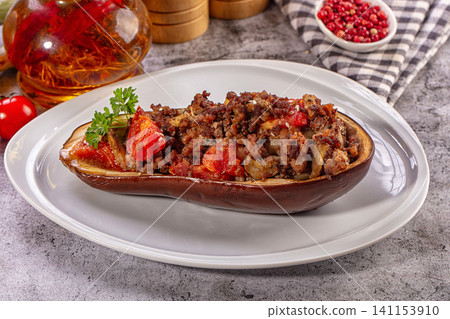Stuffed eggplant with minced meat and tomatoes on white plate with saffron oil and peppercorns Stuffed eggplant with minced meat and tomatoes on white plate with saffron oil and peppercorns 141153910