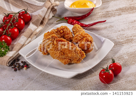Crispy fried chicken pieces on white plate with cherry tomatoes and red chili peppers Crispy fried chicken pieces on white plate with cherry tomatoes and red chili peppers 141153923