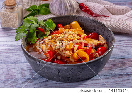 Chicken stir fry with bell peppers peanuts and cilantro in rustic bowl Chicken stir fry with bell peppers peanuts and cilantro in rustic bowl 141153954