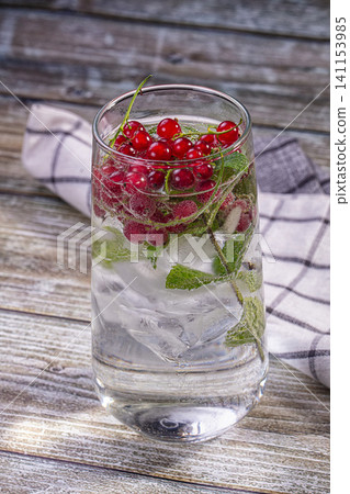 Red currant and mint infused water in glass with ice on rustic wood Red currant and mint infused water in glass with ice on rustic wood 141153985