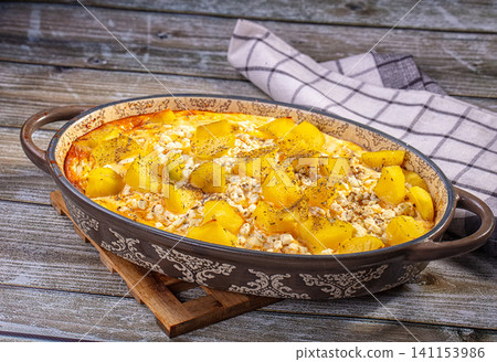 Baked potato and cottage cheese casserole in ceramic dish on rustic wooden table Baked potato and cottage cheese casserole in ceramic dish on rustic wooden table 141153986