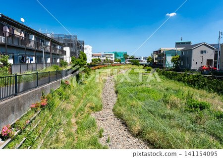 在晴朗的春日天空下,東京調布市柴崎市,乾燥的野川河畔的居民區。 在晴朗的春日天空下,東京調布市柴崎市,乾燥的野川河畔的居民區。 141154095