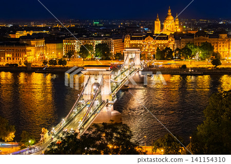 A dazzling night view of the Széchenyi Chain Bridge and St. Stephen's Basilica from the Royal Castle Hill in Budapest, Hungary. A dazzling night view of the Széchenyi Chain Bridge and St. Stephen's Basilica from the Royal Castle Hill in Budapest, Hungary. 141154310