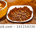 Cup of coffee decorated with a heart and coffee beans on a white plate 141154336
