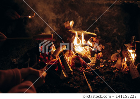 Roasting Sausages Over Campfire at Night Gathering Roasting Sausages Over Campfire at Night Gathering 141155222