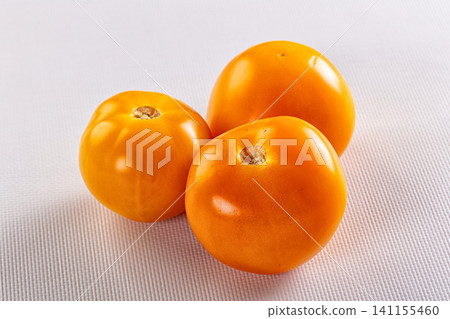Three ripe orange tomatoes on textured white surface Three ripe orange tomatoes on textured white surface 141155460