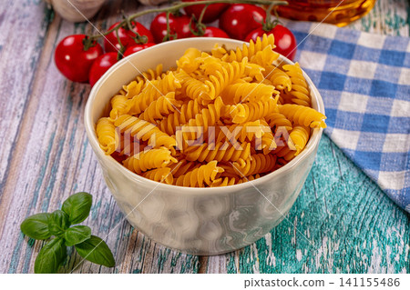 Fusilli pasta in ceramic bowl with cherry tomatoes basil and checkered cloth on rustic wood Fusilli pasta in ceramic bowl with cherry tomatoes basil and checkered cloth on rustic wood 141155486