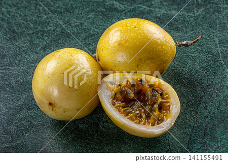 Yellow passion fruit whole and sliced on dark green textured surface Yellow passion fruit whole and sliced on dark green textured surface 141155491