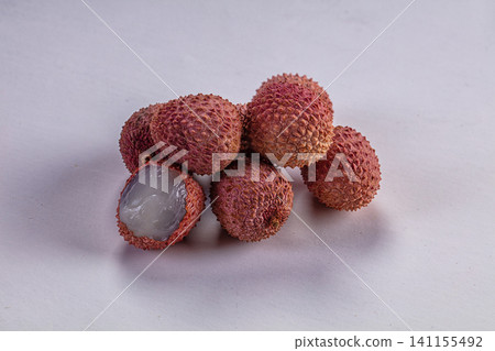 Fresh lychee fruits with one peeled showing translucent flesh on white background Fresh lychee fruits with one peeled showing translucent flesh on white background 141155492