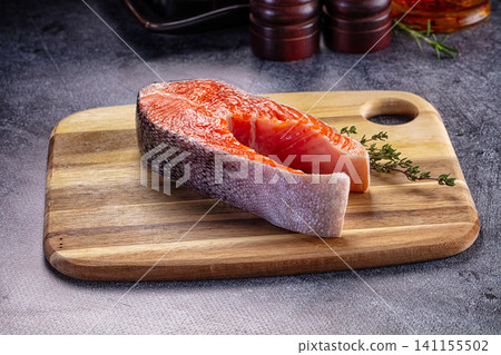 Fresh salmon fillet on wooden cutting board with herbs Fresh salmon fillet on wooden cutting board with herbs 141155502