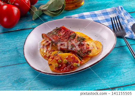 Sea perch fillet with potato slices and tomato sauce on rustic plate 141155505