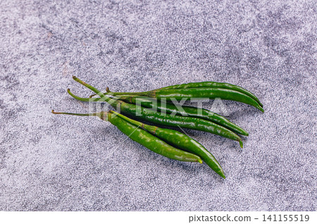 Fresh green chili peppers on textured gray surface Fresh green chili peppers on textured gray surface 141155519