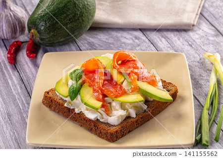 Avocado and smoked salmon toast on rustic bread with cream cheese and basil 141155562