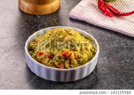 Bowl of fresh guacamole with red pepper pieces on dark surface Bowl of fresh guacamole with red pepper pieces on dark surface 141155568