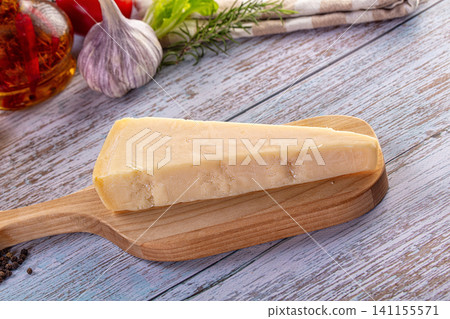 Italian hard cheese on a rustic wooden table with fresh culinary ingredients Italian hard cheese on a rustic wooden table with fresh culinary ingredients 141155571