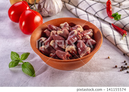 Raw chicken hearts in a clay bowl with fresh tomatoes, garlic, and herbs for cooking Raw chicken hearts in a clay bowl with fresh tomatoes, garlic, and herbs for cooking 141155574