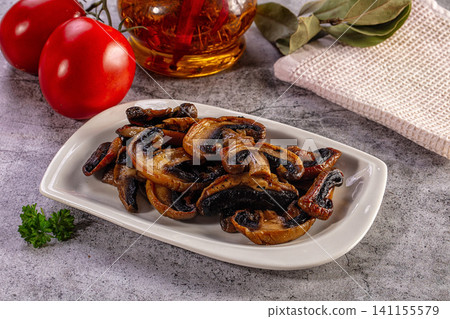Grilled or sauteed sliced mushrooms on a white plate with fresh tomatoes, herbs, and olive oil on a gray table Grilled or sauteed sliced mushrooms on a white plate with fresh tomatoes, herbs, and olive oil on a gray table 141155579