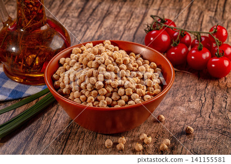 Bowl of chickpeas, fresh cherry tomatoes, olive oil, and green onions on rustic wooden table Bowl of chickpeas, fresh cherry tomatoes, olive oil, and green onions on rustic wooden table 141155581