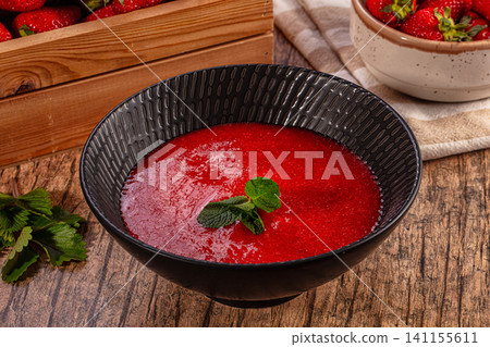Strawberry soup in black bowl with mint garnish on rustic wood table Strawberry soup in black bowl with mint garnish on rustic wood table 141155611