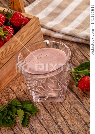 Strawberry smoothie in glass with fresh berries on wooden table Strawberry smoothie in glass with fresh berries on wooden table 141155612