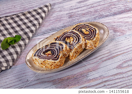 Sliced sesame coated pastry roll with chocolate swirl and nuts on ceramic plate Sliced sesame coated pastry roll with chocolate swirl and nuts on ceramic plate 141155618