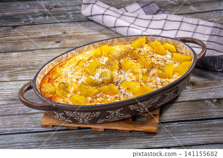 Baked potato and cottage cheese casserole in ceramic dish on rustic wood table Baked potato and cottage cheese casserole in ceramic dish on rustic wood table 141155682
