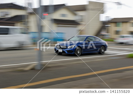 鏡頭緩緩搖攝一輛藍色雙門轎車駛過十字路口。 鏡頭緩緩搖攝一輛藍色雙門轎車駛過十字路口。 141155820