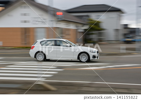 Panning shot of a white passenger car driving through an intersection. Panning shot of a white passenger car driving through an intersection. 141155822