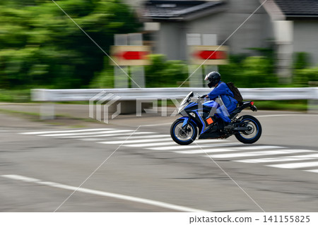 Panning shot of a sports bike turning right at an intersection. Panning shot of a sports bike turning right at an intersection. 141155825