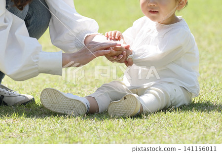 一位母親正在草地上擦拭女兒的手。 一位母親正在草地上擦拭女兒的手。 141156011