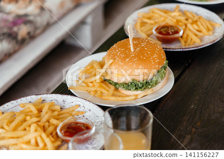 Close up of delicious cheese burger on plate with french fries. Close up of delicious cheese burger on plate with french fries. 141156227
