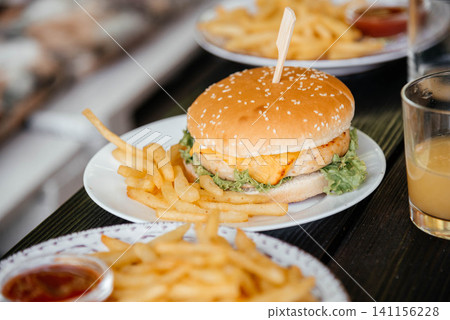 Close up of delicious cheese burger on plate with french fries. Close up of delicious cheese burger on plate with french fries. 141156228