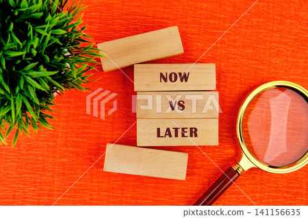 Wooden blocks state now vs later placed on a bright orange table next to a magnifying glass. A small plant is nearby creating a simple setup for decision making Wooden blocks state now vs later placed on a bright orange table next to a magnifying glass. A small plant is nearby creating a simple setup for decision making 141156635