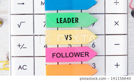 Colored arrows show the terms leader and follower in a workspace. The setting includes a calculator and office supplies, suggesting a focus on work and organization Colored arrows show the terms leader and follower in a workspace. The setting includes a calculator and office supplies, suggesting a focus on work and organization 141156640