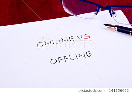 A paper shows the words online versus offline. Writing tools are nearby, suggesting a session focused on communication methods and their impacts A paper shows the words online versus offline. Writing tools are nearby, suggesting a session focused on communication methods and their impacts 141156652