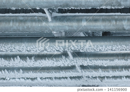 Frozen ice crystals formed on metal pipes in winter close up Frozen ice crystals formed on metal pipes in winter close up 141156900