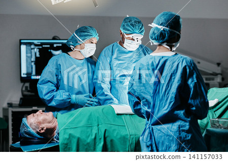Healthcare, surgery and team of doctors with patient in theater for emergency medical procedure. Hospital, cooperation and professional surgical staff for operation on senior person together in ICU Healthcare, surgery and team of doctors with patient in theater for emergency medical procedure. Hospital, cooperation and professional surgical staff for operation on senior person together in ICU 141157033