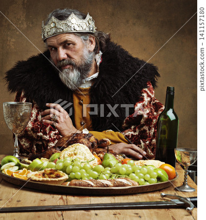 King, confident and feast in table with wine as royalty on dining hall for tradition, culture and meal in palace. Portrait, monarch and leader with eating buffet or supper with sword for chicken King, confident and feast in table with wine as royalty on dining hall for tradition, culture and meal in palace. Portrait, monarch and leader with eating buffet or supper with sword for chicken 141157180