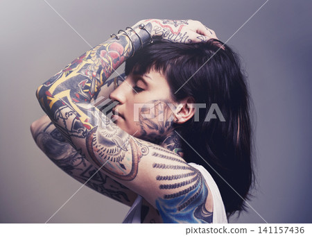 Tattoo, edgy design and rebel with woman, punk rock and tradition on a grey studio background. Profile, person and model with ideas or creative with emo and gothic art with ink, trendy or heavy metal Tattoo, edgy design and rebel with woman, punk rock and tradition on a grey studio background. Profile, person and model with ideas or creative with emo and gothic art with ink, trendy or heavy metal 141157436