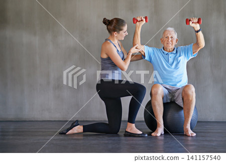 Senior man, dumbbells or physical therapy for health, fitness or medical assessment on wall background. Physiotherapy, support or weights by old patient with gym ball for balance, healing or recovery Senior man, dumbbells or physical therapy for health, fitness or medical assessment on wall background. Physiotherapy, support or weights by old patient with gym ball for balance, healing or recovery 141157540