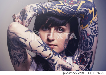 Tattoo, portrait and woman with culture, rebel and heavy metal on a grey studio background. Face, person and unique with edgy clothes and gothic design with confidence and artistic with tradition Tattoo, portrait and woman with culture, rebel and heavy metal on a grey studio background. Face, person and unique with edgy clothes and gothic design with confidence and artistic with tradition 141157638