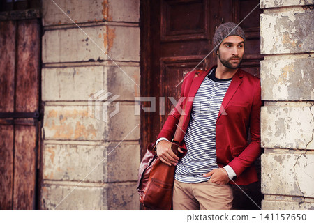 Man, fashion and model in city with confidence, trendy style or winter accessories with bag outdoor. Urban, unique and stylish with designer clothes, edgy and chic with wool hat or beanie for weather Man, fashion and model in city with confidence, trendy style or winter accessories with bag outdoor. Urban, unique and stylish with designer clothes, edgy and chic with wool hat or beanie for weather 141157650