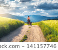 Woman with mountain bike standing on dirt road. Female cyclist 141157746