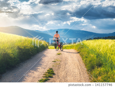 Woman with mountain bike standing on dirt road. Female cyclist 141157746